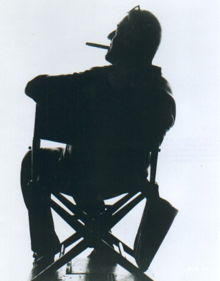 William Castle Smoking Cigar and Seated In Director's Chair